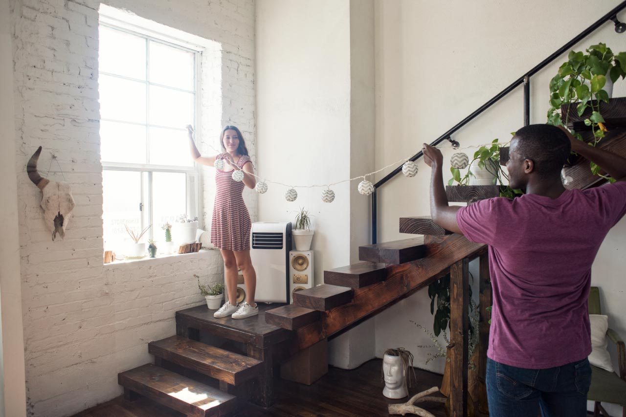 Young couple decorating loft with fairylights