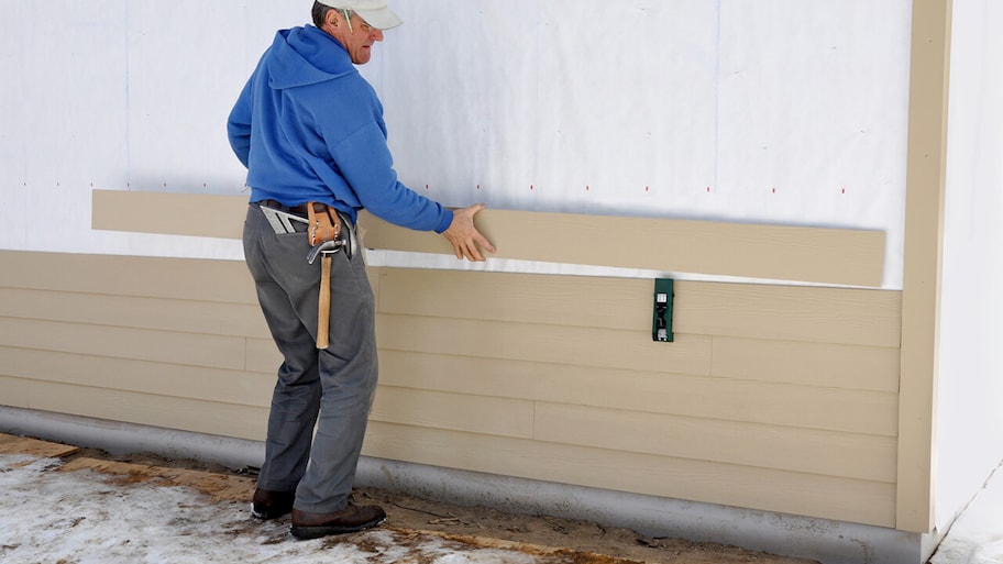 carpenter installing siding on a home