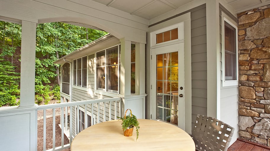 covered porch with table and chair on front entrance of home