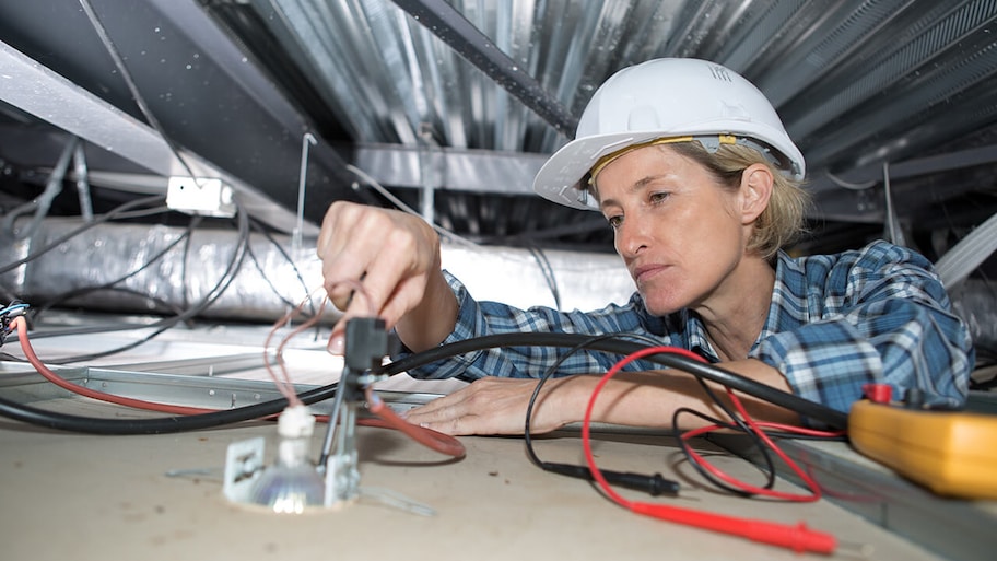 electrician installing wiring in attic of home