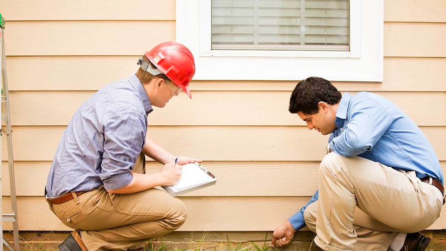 Engineer and homeowner inspecting house foundation