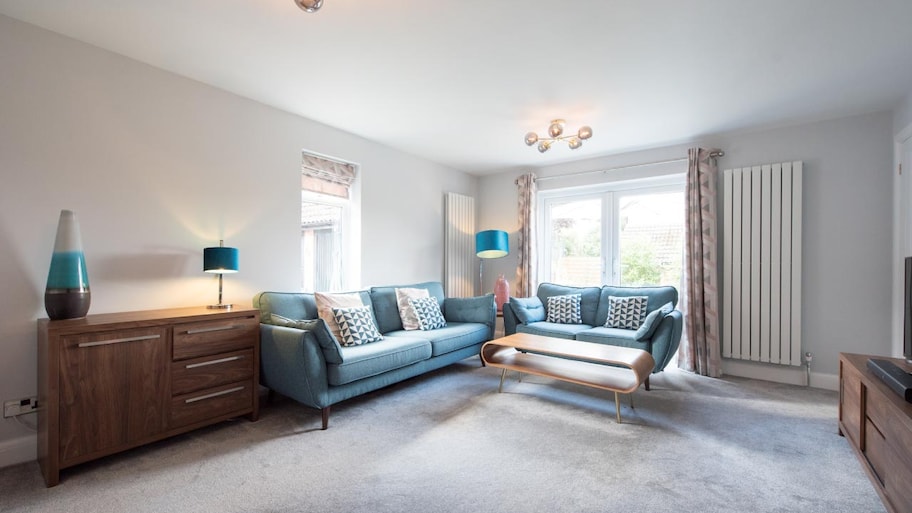 A view of a carpeted living room with retro looking blue sofa