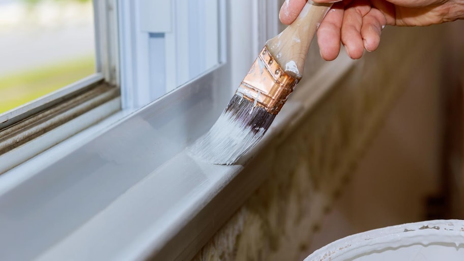 A hand painting with a brush a window trim