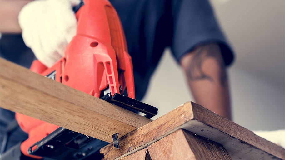 handyman cutting a board with a jigsaw for hired project