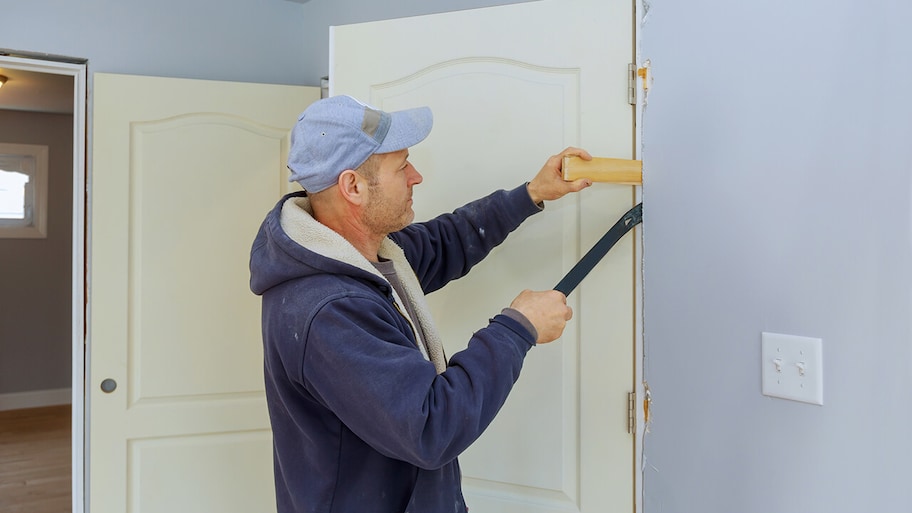 handyman repairing the interior door of a room in a house