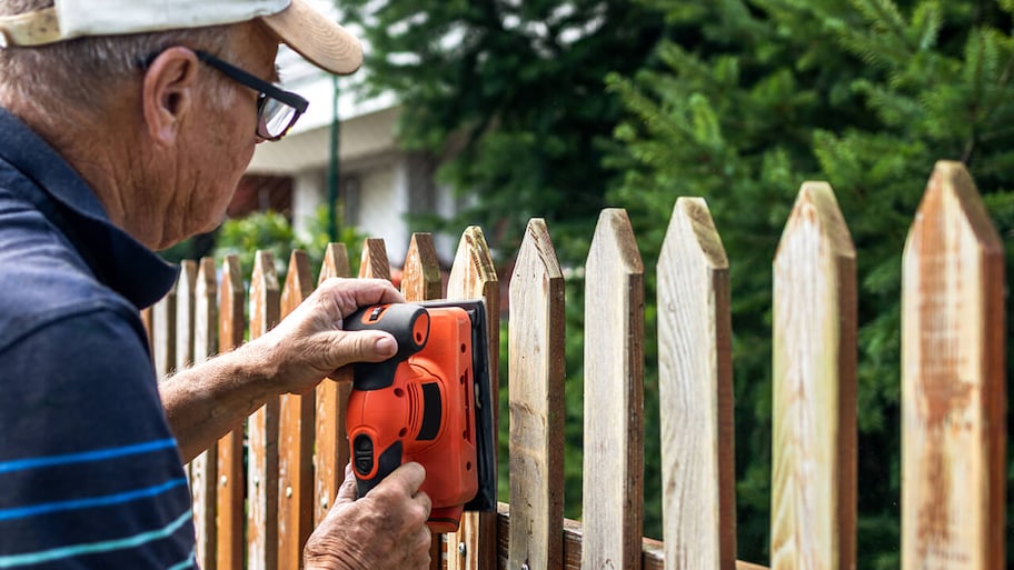 handyman repairing a wooden fence outside home