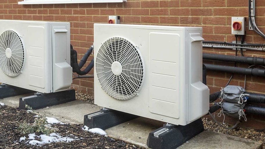 heat pumps installed on the side of a brick house