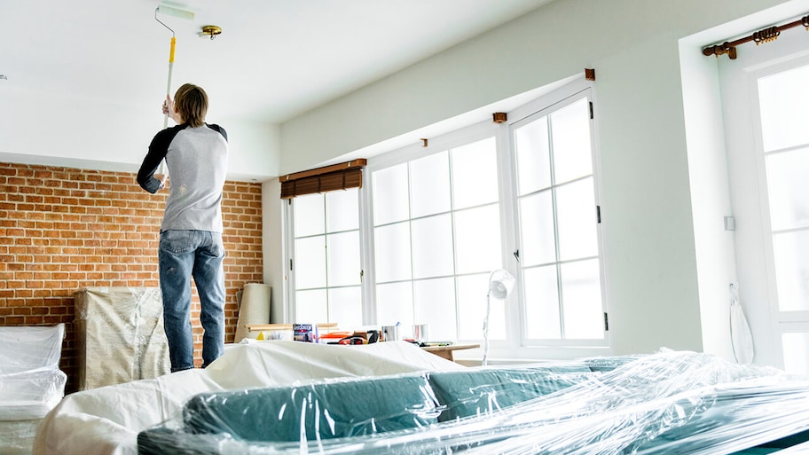 homeowner painting the ceiling of room with roller