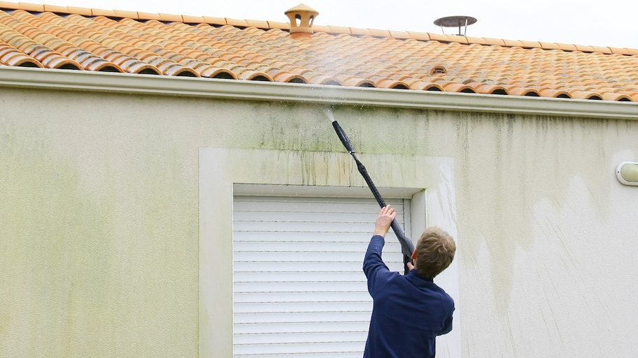 homeowner powerwashing the exterior of a stucco house