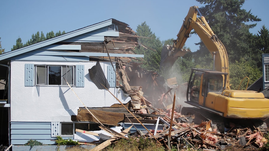 house being demolished by earth mover