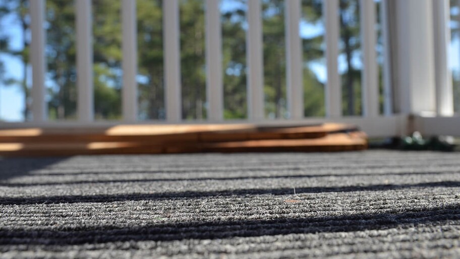 close up of indoor outdoor carpet on porch with railing