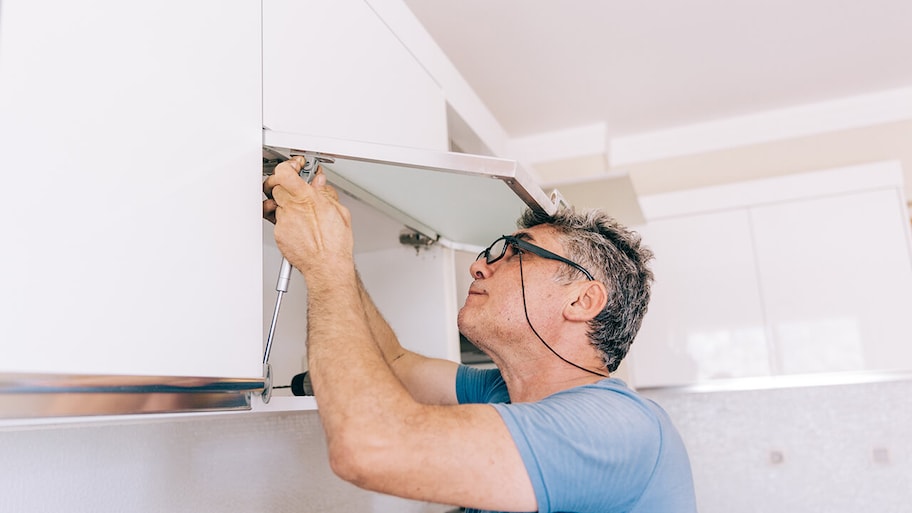 carpenter repairing kitchen cabinets