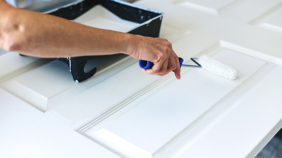 homeowner painting a door with a roller