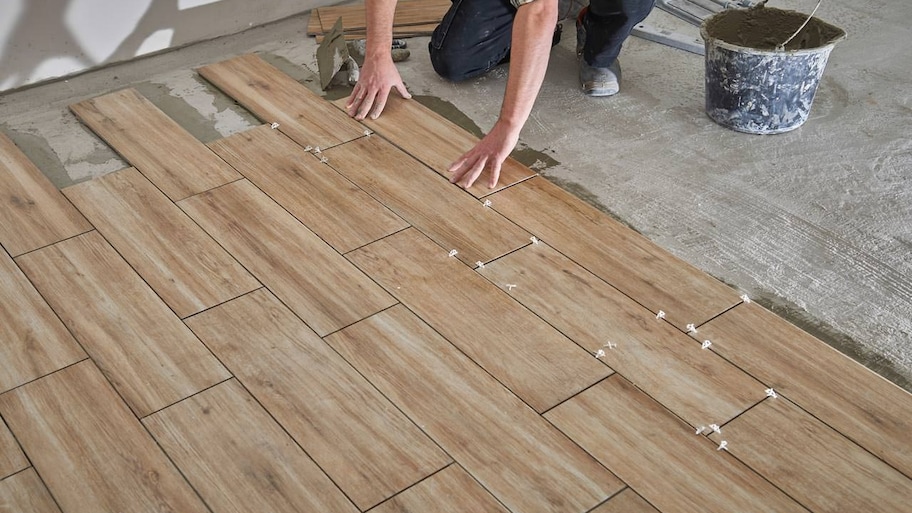 A professional installing wood tiles for flooring