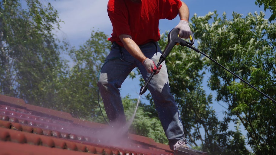 professional powerwashing the roof of a house