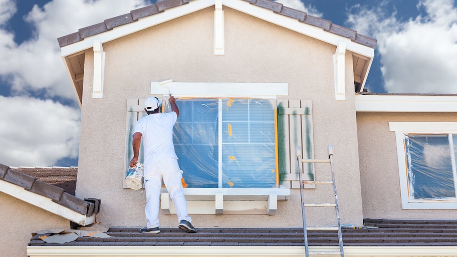 professional painting the exterior of a stucco home