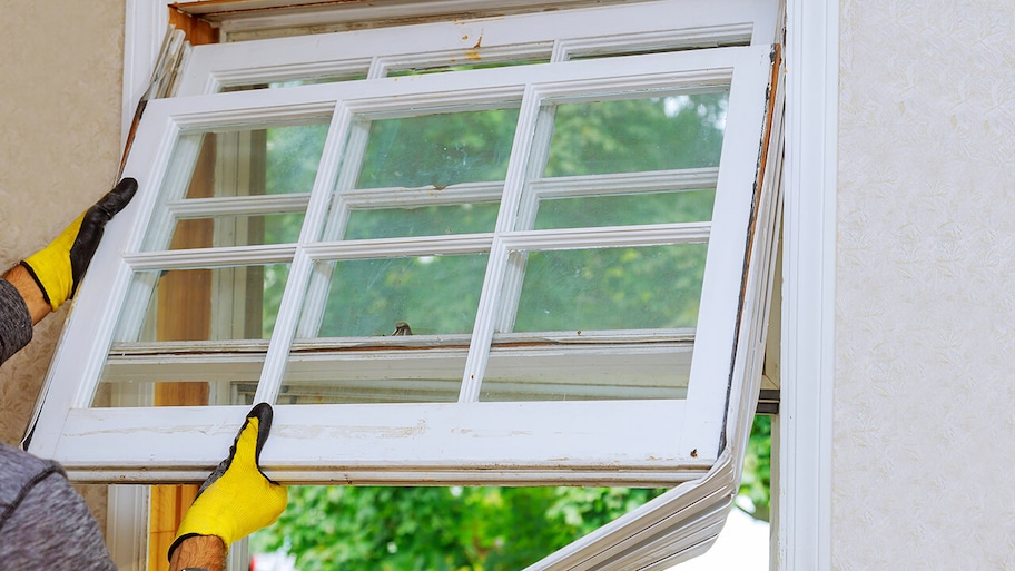 professional repairing an old window in a home