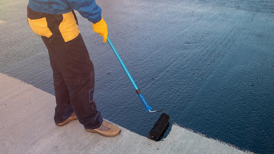 professional spreading sealant on flat roof with roller