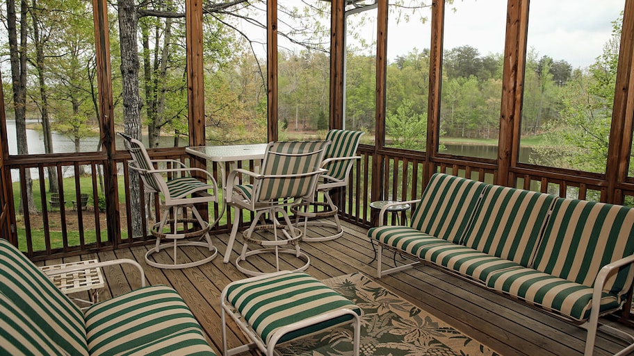 screened in porch with patio furniture and view of lake