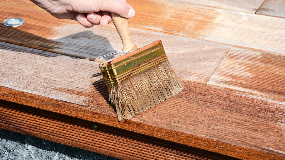 sealing a wooden deck with a paintbrush