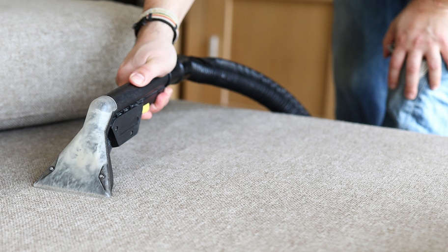 man vacuuming sofa