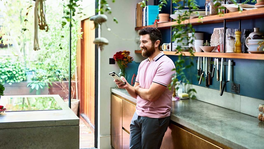 Man standing in the kitchen using phone