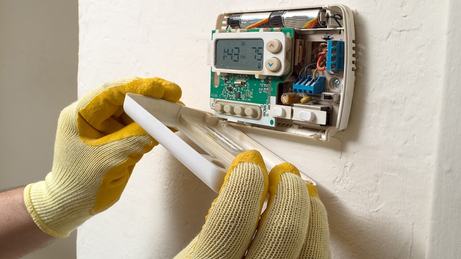 technician repairing a home digital thermostat