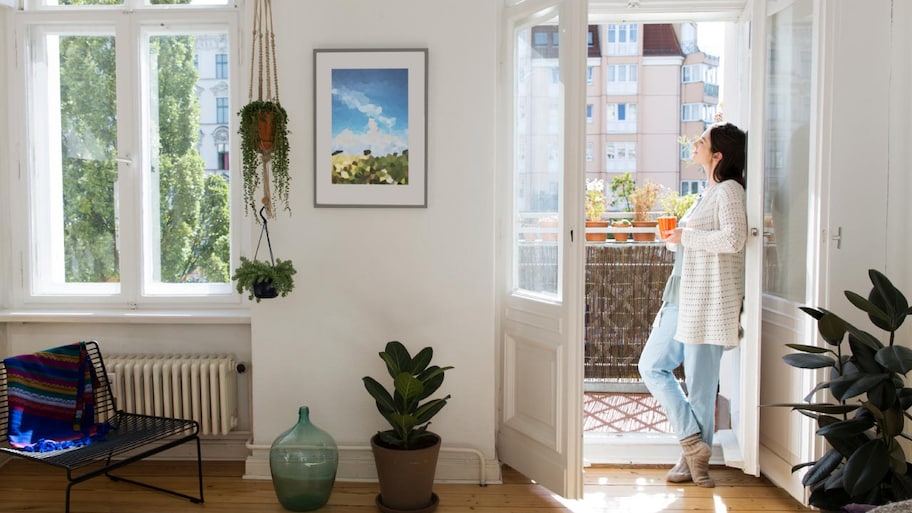 Woman at home standing at balcony door