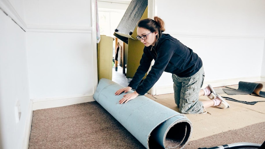 A woman rolling up old carpet