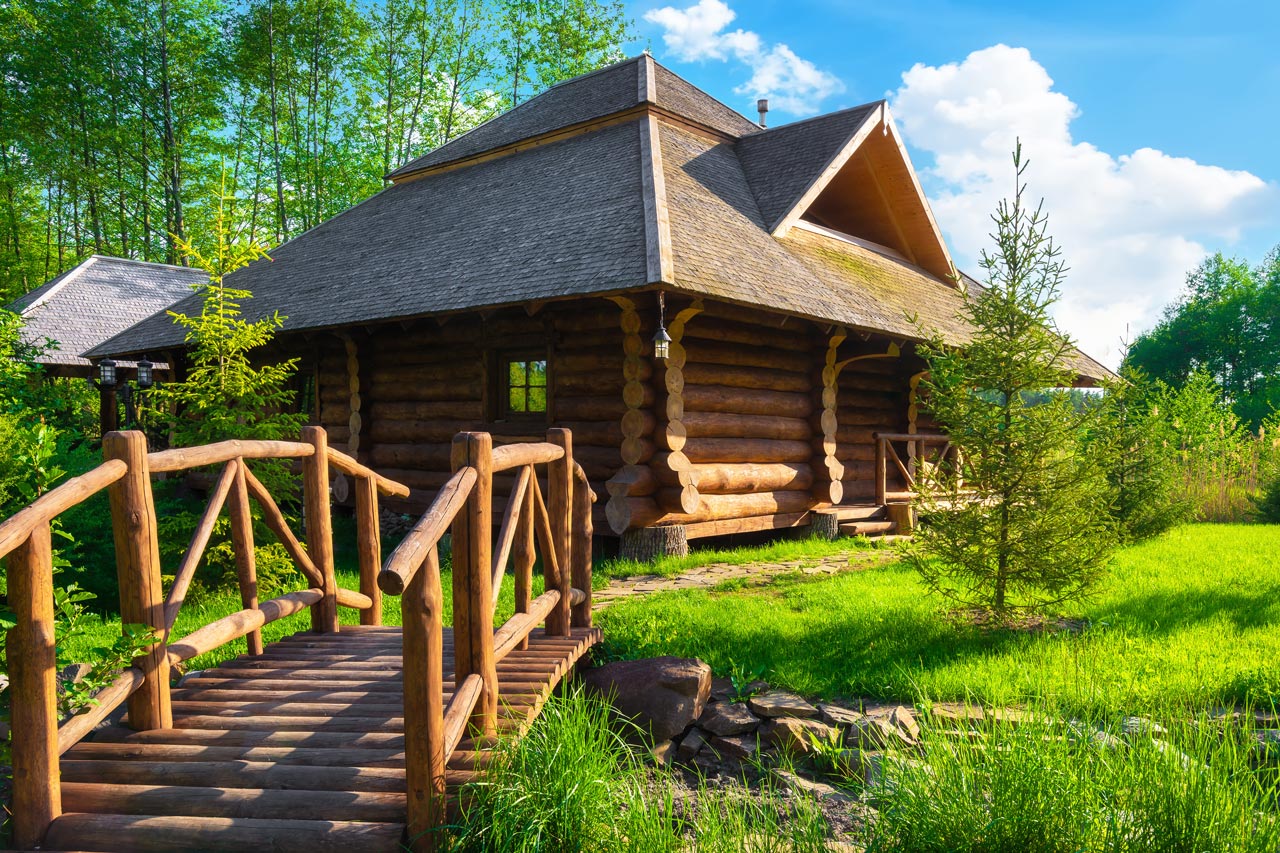 A small wooden bridge leading to a log cabin