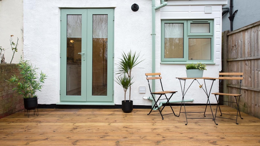 A wooden deck in the backyard of a house with a sitting area