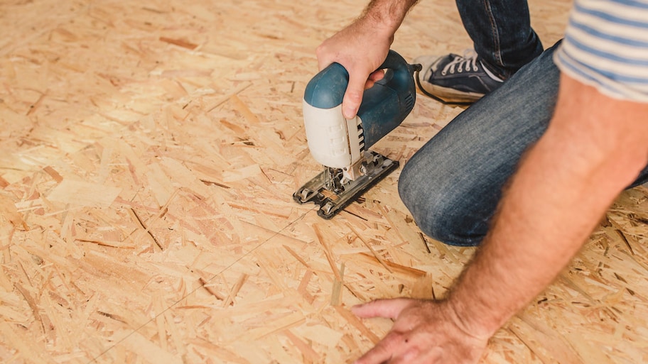 A worker installing subfloor from sheets of plywood